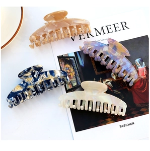 Close-up of elegant acetate hair claws in amber, purple, blue, and white patterns