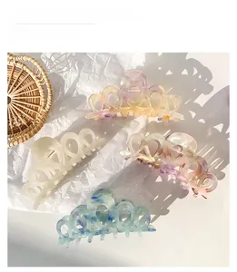 Detail of large acetate hair claws in iridescent marble and ivory colors for French styling