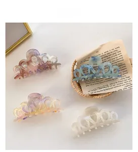 Detail view of four colorful heart-shaped acetate hair claws on a vintage newspaper background