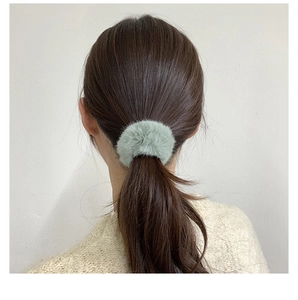 Detailed view of a soft mint green plush faux fur scrunchie on a ponytail