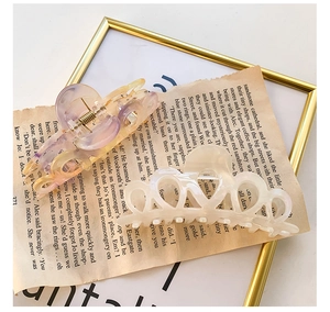 Detail view of purple marbled acetate claw clip and cream hollow heart hair clamp