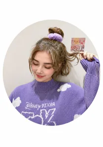 Detail view of a fluffy purple faux fur hair tie with bunny ears worn on a high ponytail
