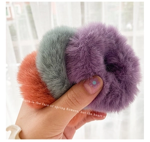 Close-up of soft plush faux fur scrunchies in purple grey and orange for winter hair styling