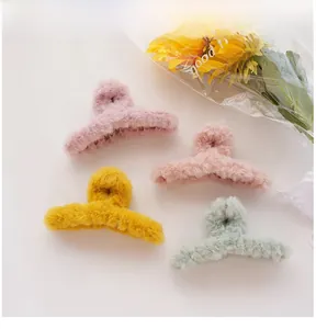 Detailed view of four colorful plush hair claws in pink, yellow and mint green tones