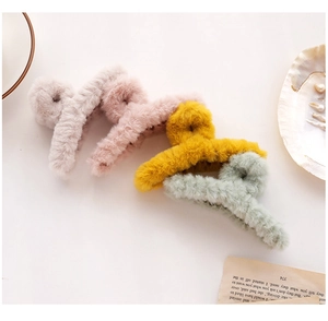 Close-up of four plush hair claws in grey, pink, yellow, and green for autumn and winter
