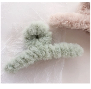 Close-up of soft plush hair claw clips in light green and pastel pink colors