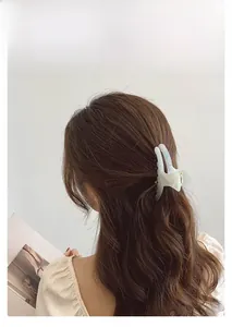 Detail view of a large cream acetate claw clip on brunette long wavy hair for women