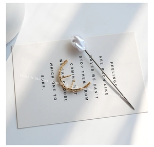 Close-up of golden textured U-shaped hair clip and silver hairpin with baroque pearl