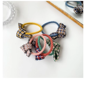 Set of four tweed bow hair ties in yellow, navy, orange, and green on white background