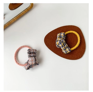 Close-up of pink and yellow tweed bow hair scrunchies with elegant fringe details