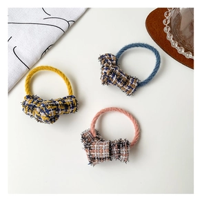 Detailed close-up of three tweed bow hair ties in yellow, blue, and pink colors