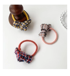 Detailed macro view of three tweed bow hair ties with elegant fringe texture and plush bands