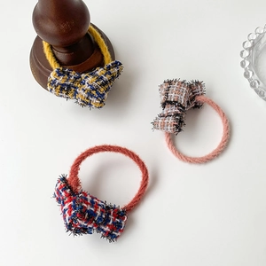 Elegant tweed bow hair ties in three plaid patterns on a minimalist white background