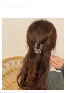 Detail of dark grey translucent geometric hair claw clip used in a half-up hairstyle