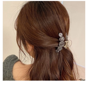 Close-up of a floral acetate shark hair claw clip styled on brown wavy hair