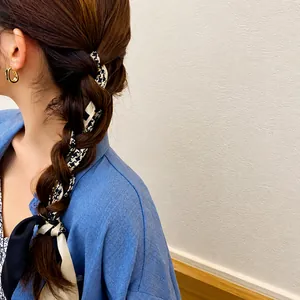 Detalle de pañuelo de seda con pata de gallo anudado como accesorio de pelo estilo retro