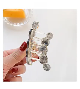 Detailed close-up showing the golden metal spring and translucent grey acetate hair claw