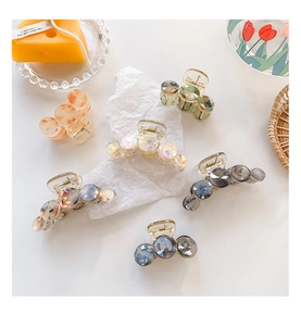 Detailed close-up of acetate hair claws with marble patterned inserts and golden springs
