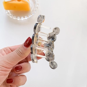 Translucent grey geometric hair claw clip with stacked circular design and gold spring