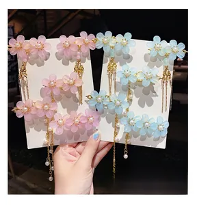 Detail of floral hair clips with frosted resin petals and elegant gold tassels