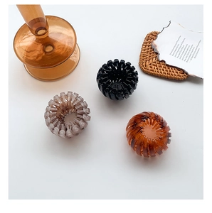 Set of three expandable bird nest hair clips in black, amber, and purple colors