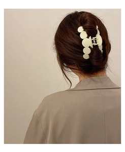 Detail of white matte multi-disc hair claw clip styled on elegant dark brown hair