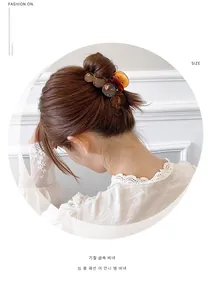 Detail showing amber resin hair claw clip worn in a half-up hairstyle for women