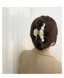 Close-up of a large cream acetate claw clip styled on a woman's hair with wavy texture