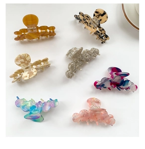 Detailed collection of assorted marble and acetate hair claw clips for women on white background