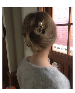 Vue détaillée d'une épingle à cheveux en métal doré en U avec une grande perle blanche