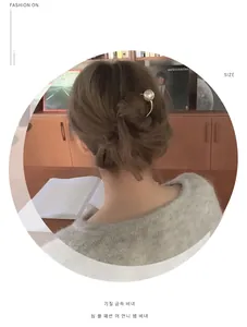 Vue détaillée d'une épingle à cheveux en métal doré en U avec une grande perle blanche