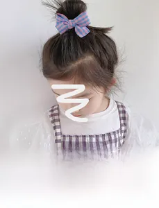 Détail d'une fille portant un nœud papillon à carreaux rose et bleu sur un chignon
