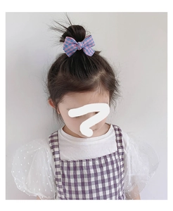 Barrette à cheveux à nœud vichy rose et bleu sur le chignon d'une petite fille