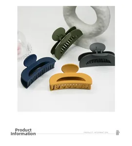 Detail of four matte finish crescent hair claws in green, blue, charcoal and yellow colors