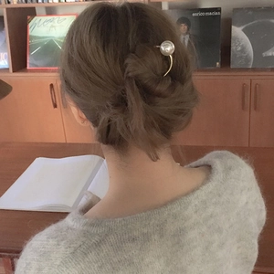 Épingle à cheveux en U dorée avec grande perle blanche dans un chignon élégant et raffiné