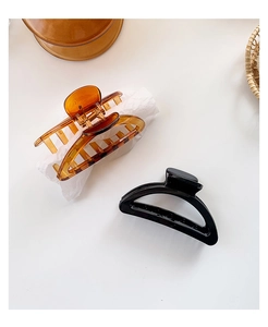 Detail of large crescent hair claws in amber and glossy black on a white surface