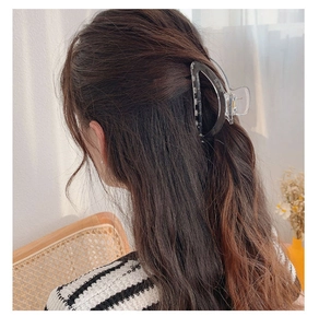 Detailed view of a large transparent crescent hair claw clip holding long wavy hair in place