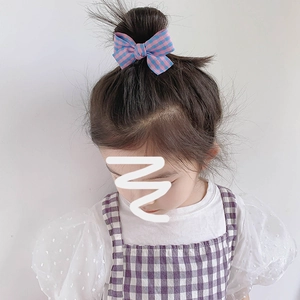 Lot de trois pinces à cheveux à nœud à carreaux pour filles, portées par un modèle