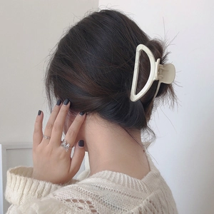 Elegant off-white D-shaped hair claw clip and silver rings styled on a female model