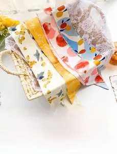 Détail de quatre foulards en soie aux motifs de fruits sur un panier d'été fleuri