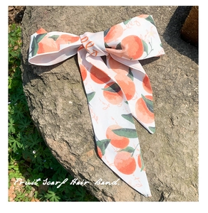 Détail d'un foulard à cheveux imprimé fruits avec motifs oranges sur un rocher