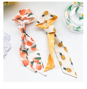 Détail de foulards en soie avec motifs pêche et ananas sur fond de dentelle blanche