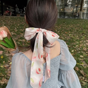 Ruban à cheveux en soie rose avec motif de pêche attaché en nœud sur une queue de cheval