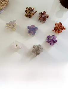 Flat lay of eight mini acetate flower hair clips in various marble and tortoiseshell patterns