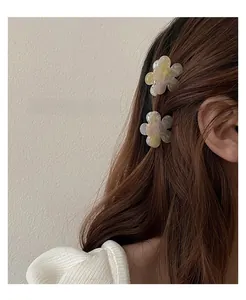 Detail of floral acetate hair claws with marble texture in purple and yellow on hair