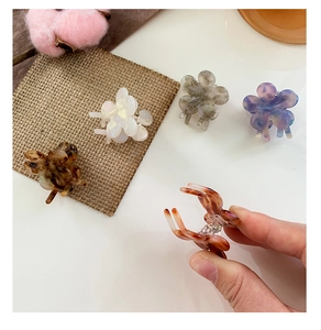 Close-up of mini acetate flower hair claws with marble texture and metal spring detail