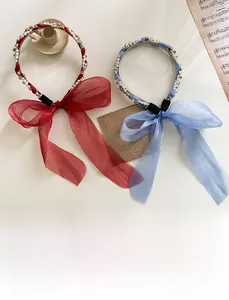 Détail de serre-têtes en perles et strass avec grands nœuds en rouge vin et bleu clair