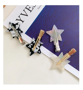 Detailed view of star-shaped acetate hair clips with marble patterns and metal duckbill base
