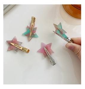 Detail showing star-shaped marble pattern hair clips with metallic duckbill base