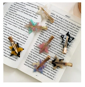 Detailed view of star-shaped acetate hair clips with diverse marble patterns on a book